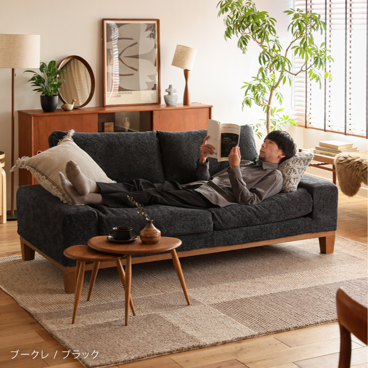 オットマンに足を乗せてソファーでくつろぐ男性.jpg